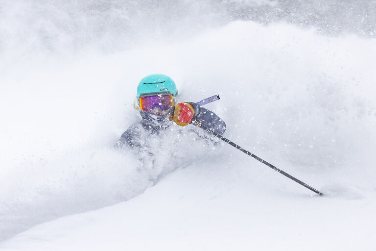 Woman skier in deep powder wearing Giro helmet and goggles